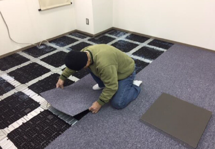 新しいタイルカーペットを職人がはっている様子